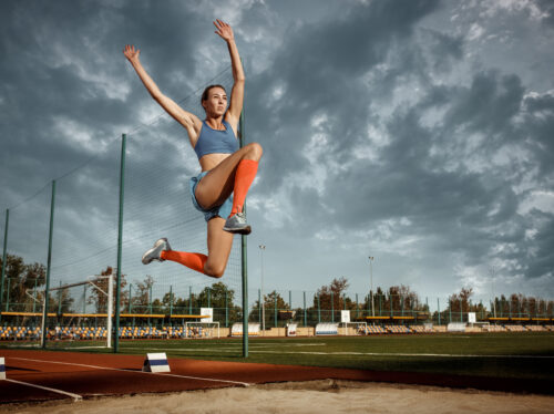 Female athlete performing a long jump during a competition Female athlete performing a long jump during a competition