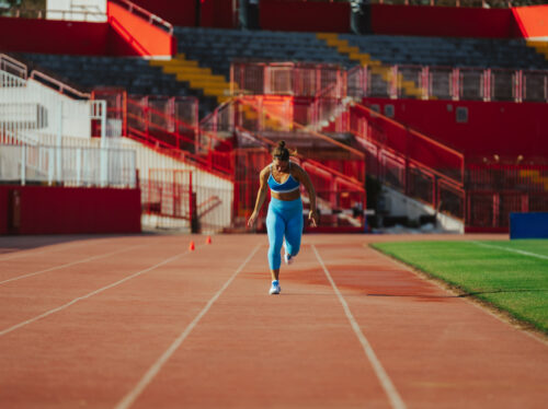 Portrait of a female runner in a blue active wear racing at the stadium Portrait of a female runner in a blue active wear racing at the stadium